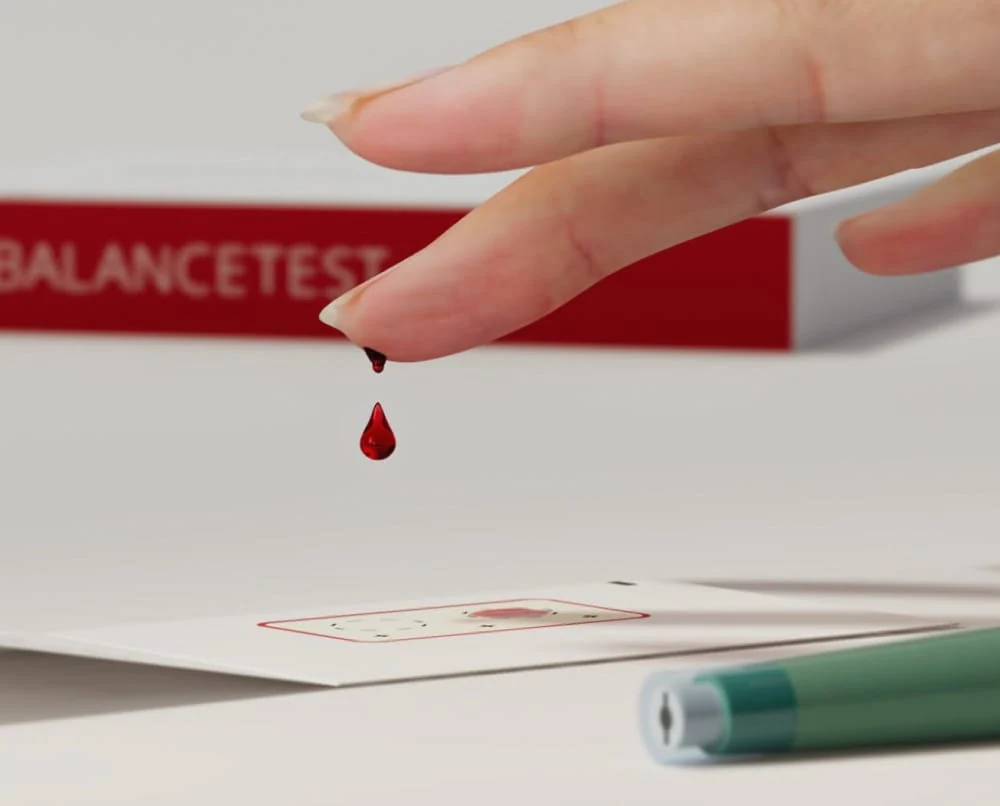 Goutte de sang au-dessus de la carte de prélèvement BalanceTest, visuel officiel Zinzino