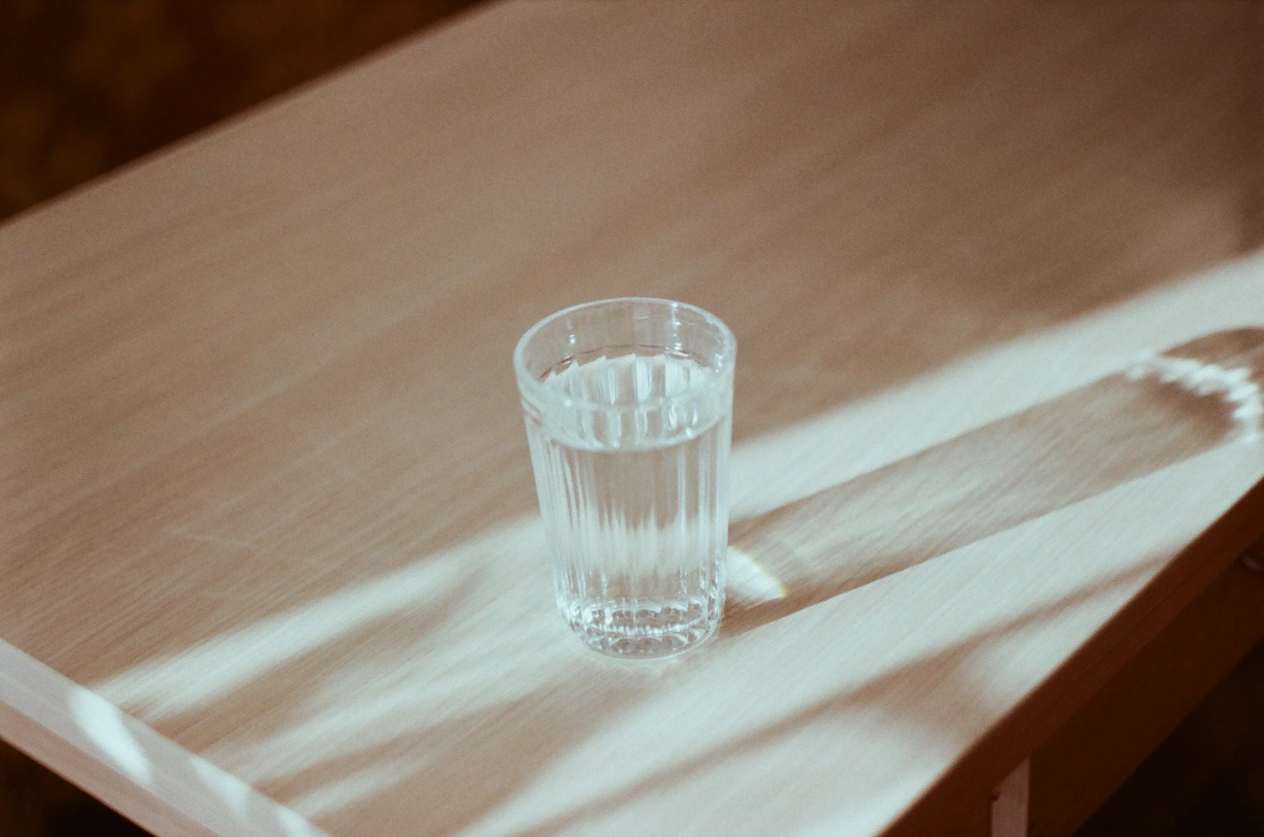 Verre d’eau éclairé par une lumière naturelle sur une table en bois