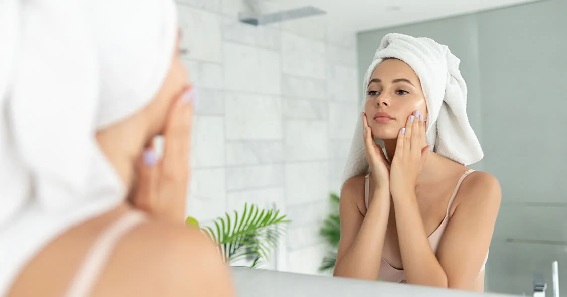 Une femme applique un soin devant un miroir
