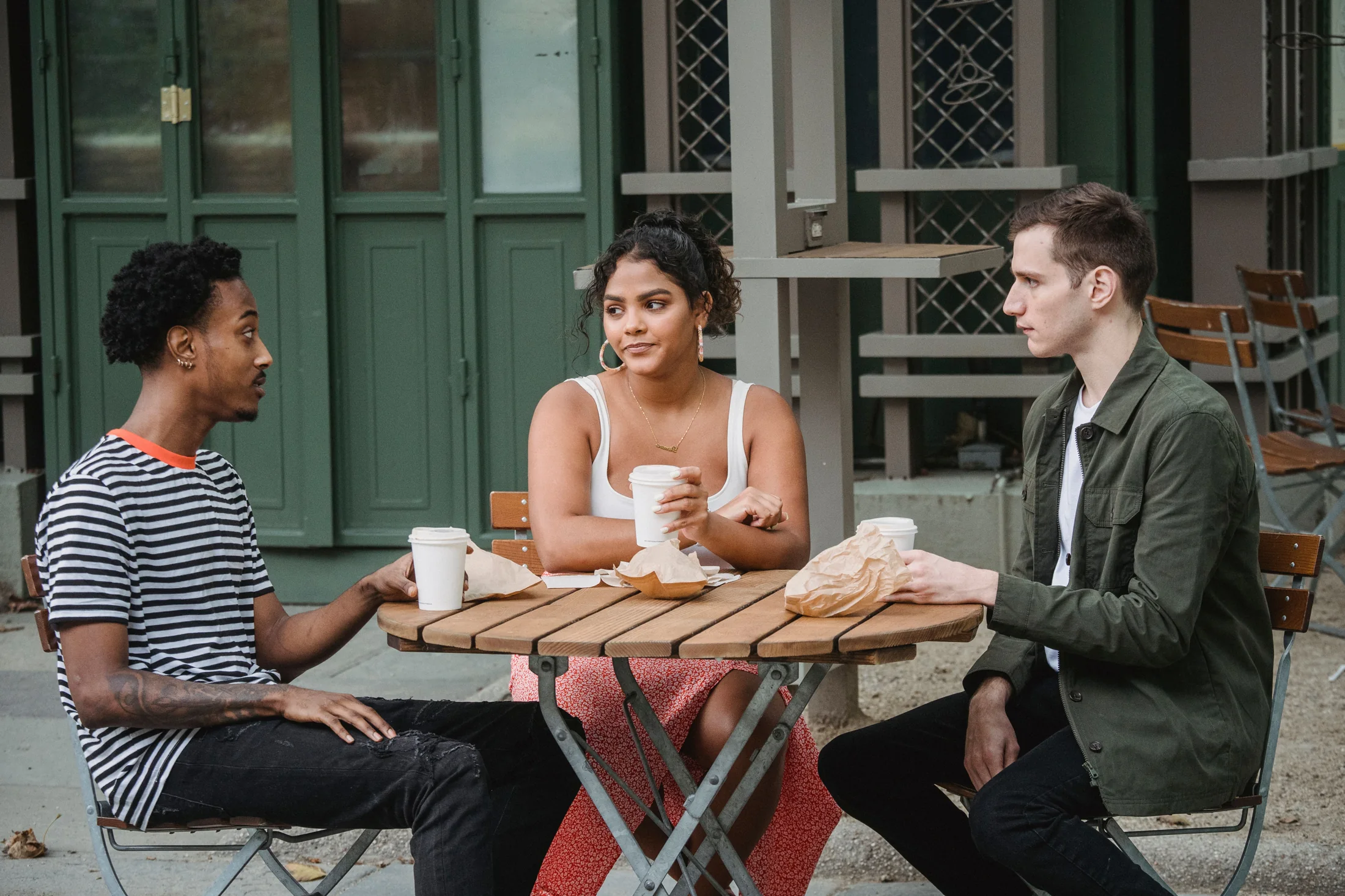 Trois adultes en conversation autour d’une table de café