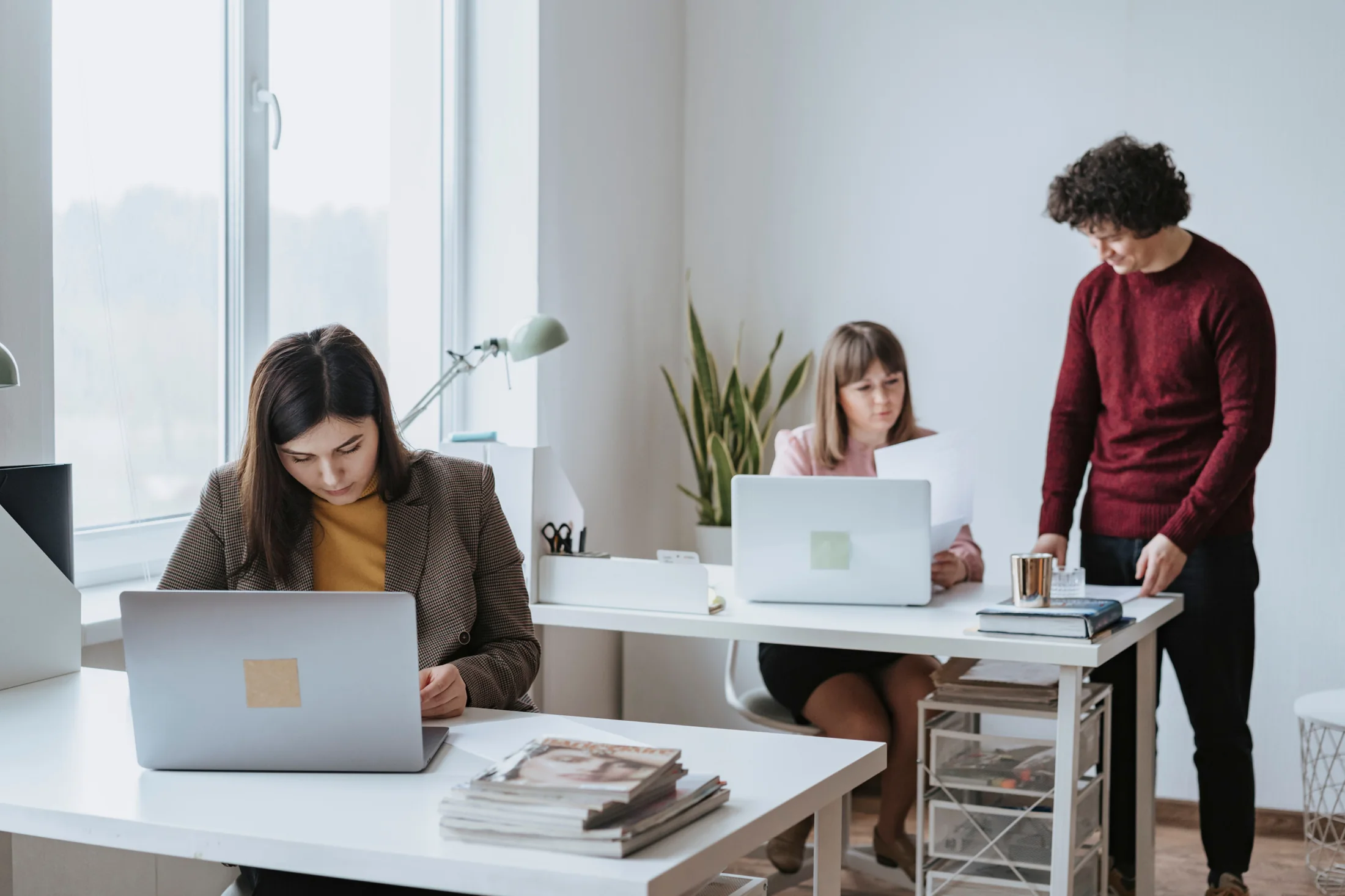 Une personne accompagnant deux adultes qui travaillent sur ordinateur